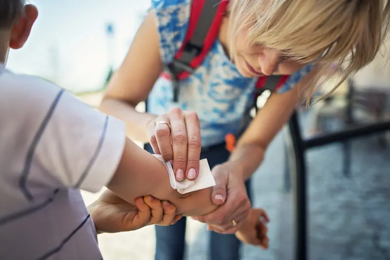 A first aider cleaning a wound on a child