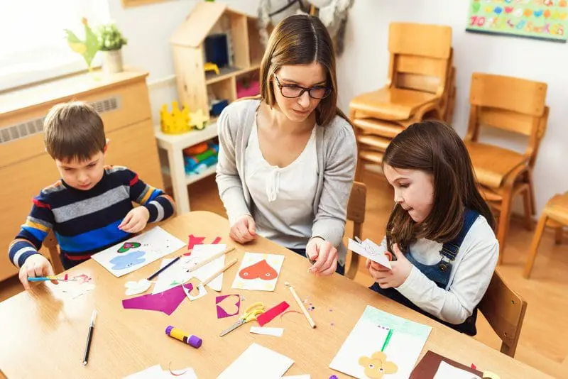 A child care worker doing craft activity with young children 