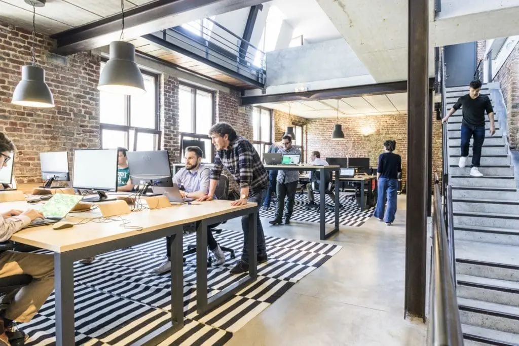 A workplace with large tables and people working together at them.
