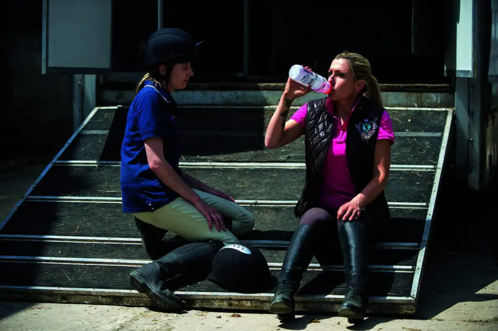 horse rider having a dink of water watched by another 