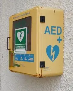 A defibrillator box on a village hall wall