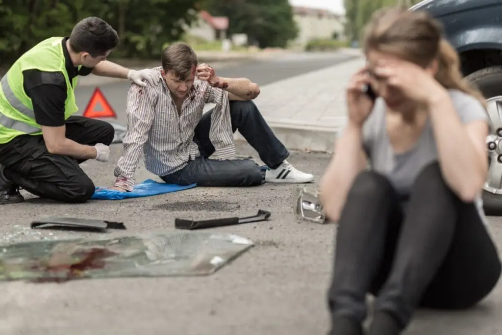 People sitting on the road after car crash RTA