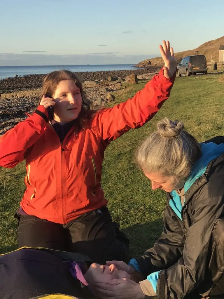Woman calling for 999 help next to a casualty