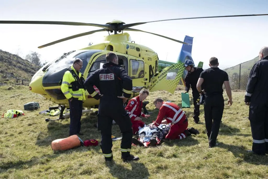 SCAA Paramedics attending a casualty with the helicopter in the background