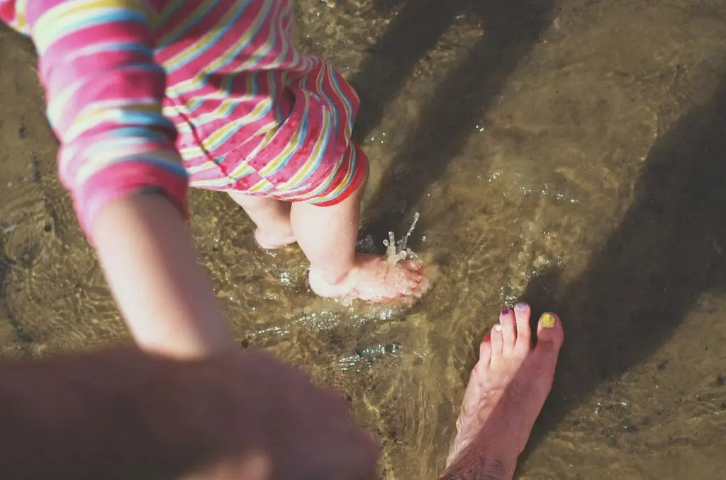 the feet of a child and adult paddling in the sea