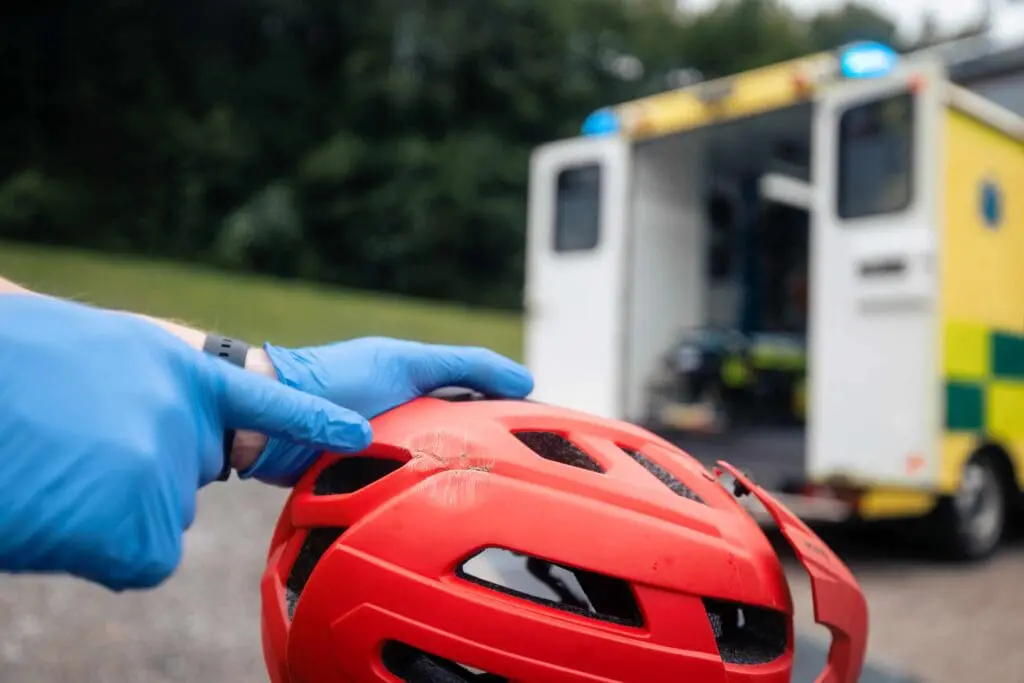 A damaged bicycle helmet with the impact area being pointed to.