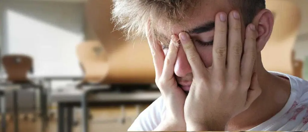 A young man with his head in his hands, stress, mental health distress