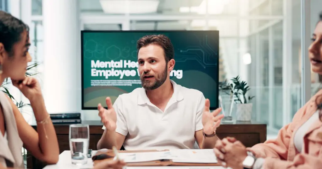 A man talking in an office meeting with Mental Health Policy banner in the background