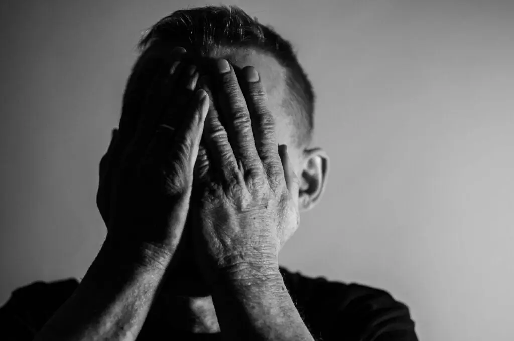 A man with his hands over his face