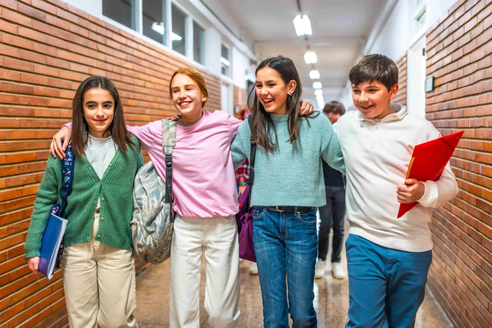 A group of teenage children walking in a corridor, holding arms.
