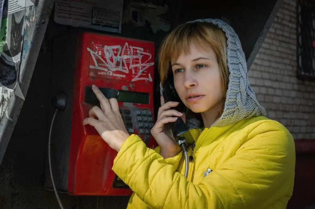 A woman using a public phone emergency - mental health