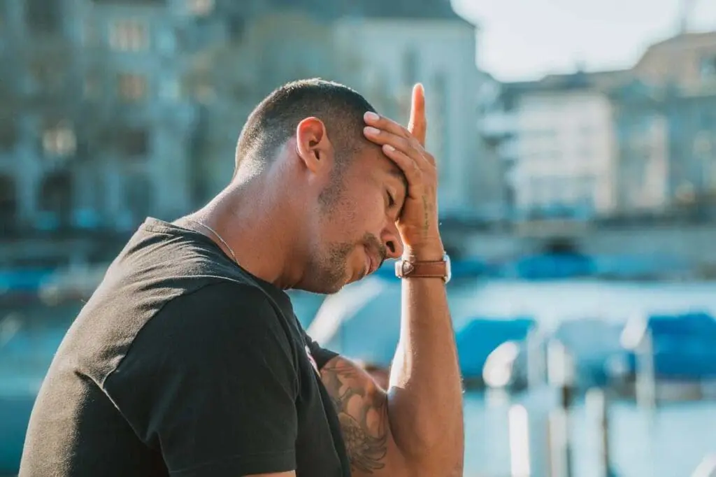 A young man holding his head in his hand. Stress, anxiety, addiction.