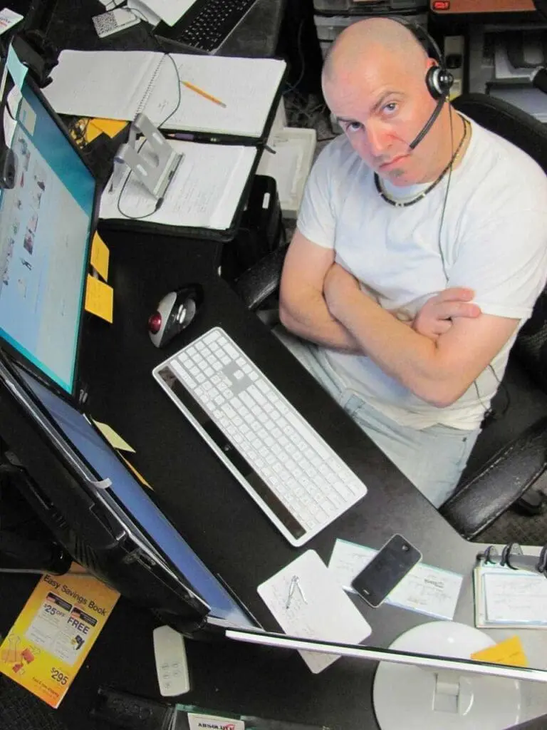 A man in a cluttered office with several computer screens
