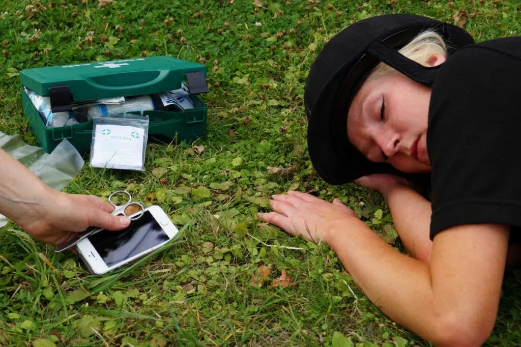 A horse rider on the ground with a first aid kit and phone nearby