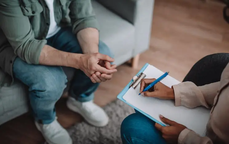 woman taking notes with man sitting on couch