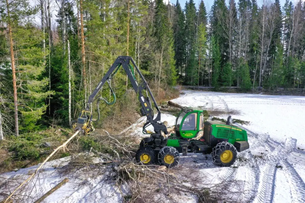 A forest machine harvesting trees in the snow