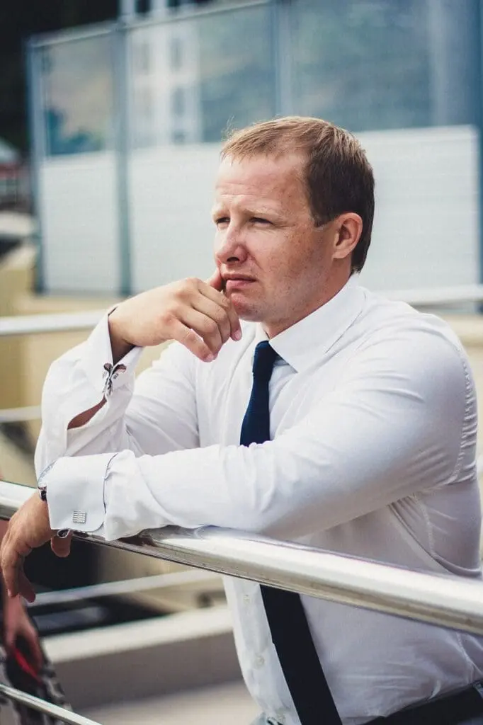 A office worker man in business attire pondering outside.