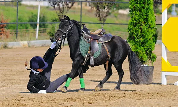 Rider falling on their bottom from horse after jump