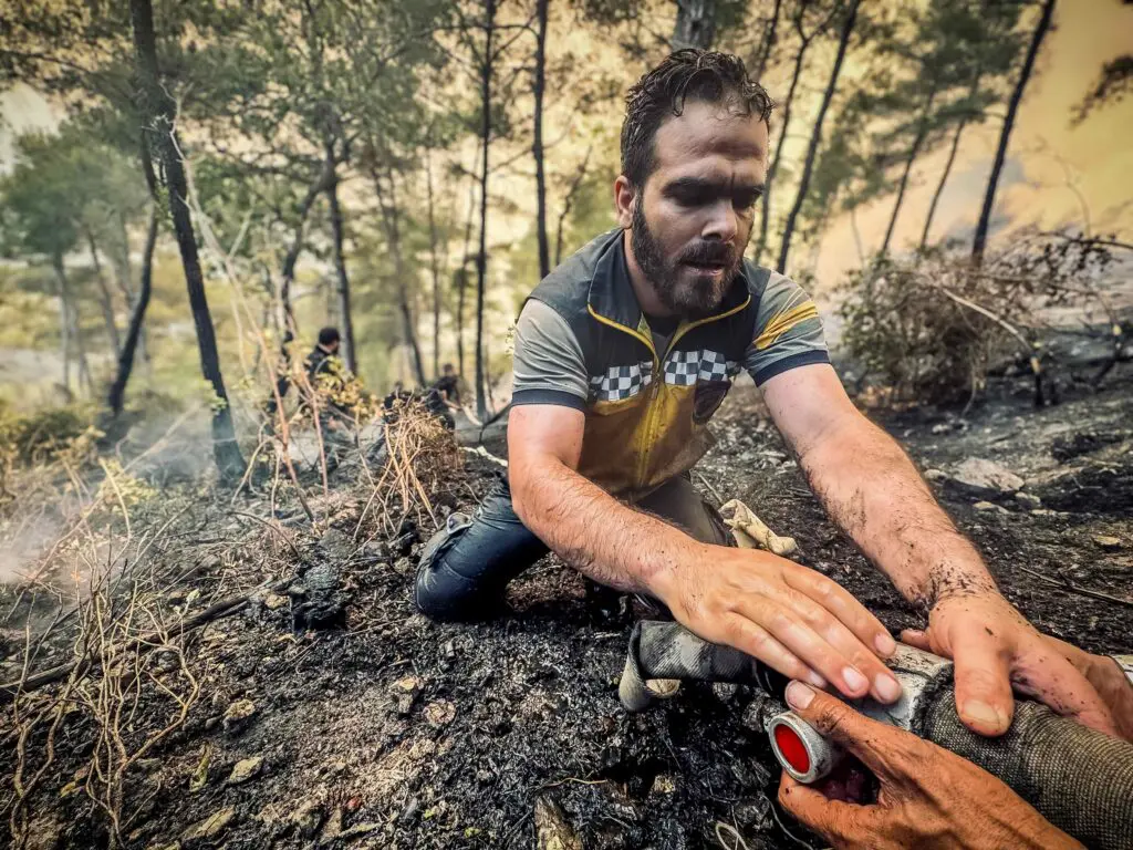 A man on a burnt out hill being pulled from danger. 